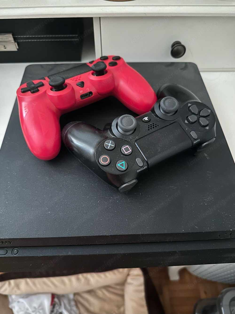 PS4 mit zwei Controllern und Spielen