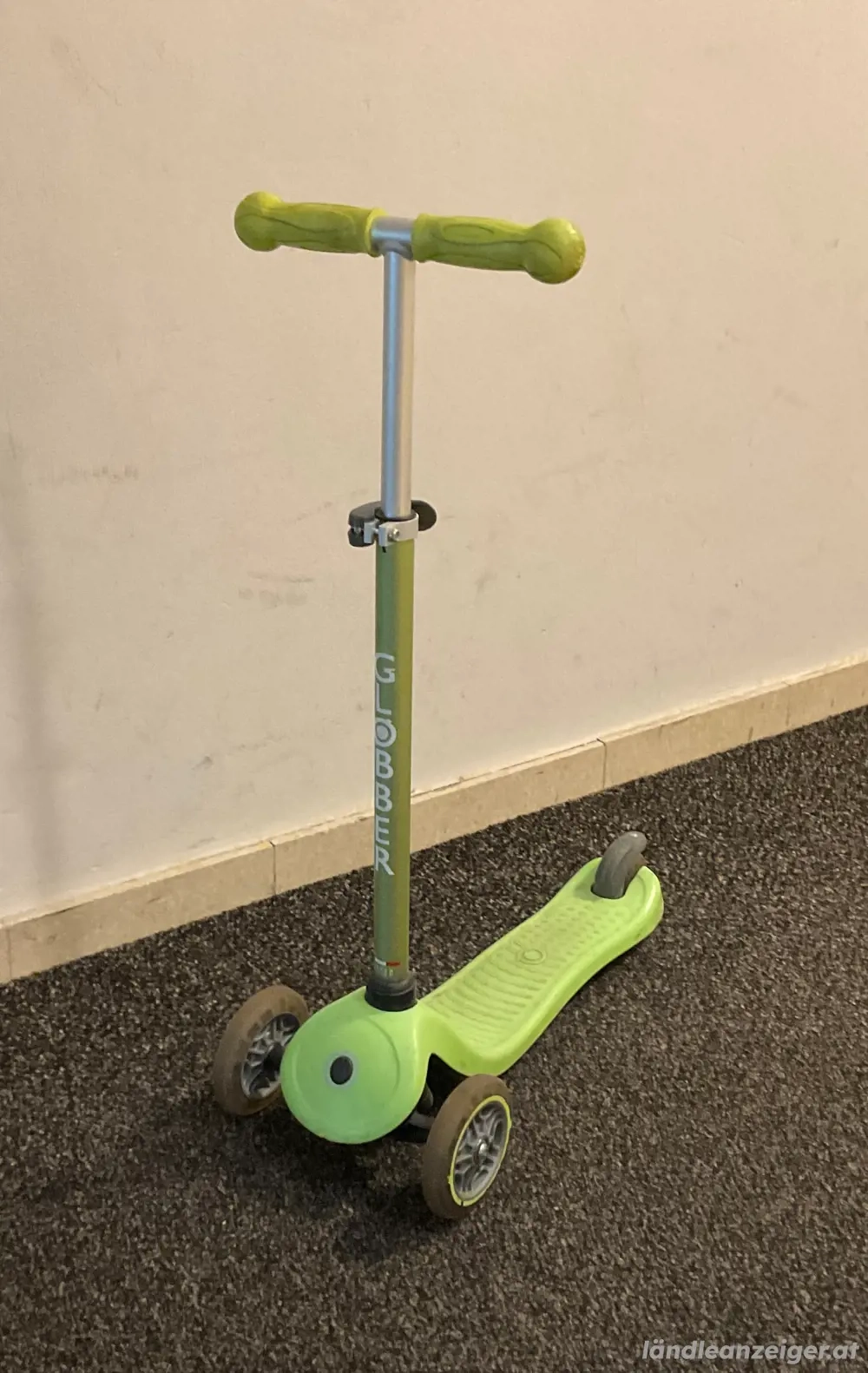 Kinderroller in Grün mit leuchtenden Rädern beim Fahren