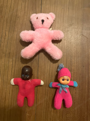 Kleine Puppen und rosa Stoffbär