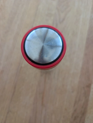 Trinkflasche aus klarem Glas mit einem roten Schraubdeckel.