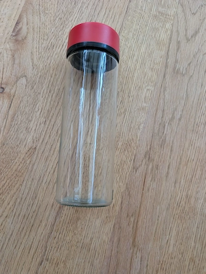 Trinkflasche aus klarem Glas mit einem roten Schraubdeckel. Bild 2